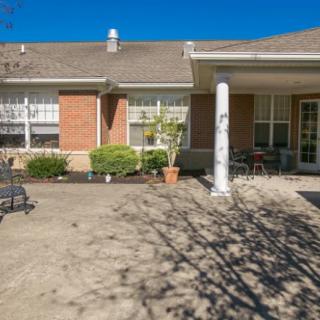 A sunny view of a house with a brick exterior and a spacious patio area.