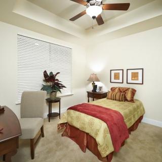 A cozy bedroom featuring a single bed with colorful bedding, a ceiling fan, and elegant decor.