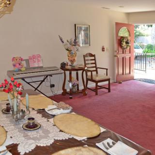 A cozy dining room with a set table and natural light streaming through the doorway.