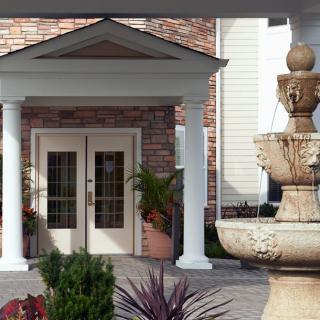 A building entrance with decorative columns and a nearby fountain.