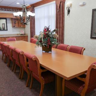 A well-furnished conference room featuring a long wooden table and comfortable chairs, ideal for meetings.