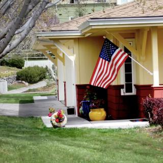 A suburban house with an American flag hanging outside and a well-maintained front yard.