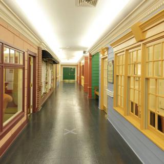 A brightly lit indoor hallway featuring various window displays and architectural elements.