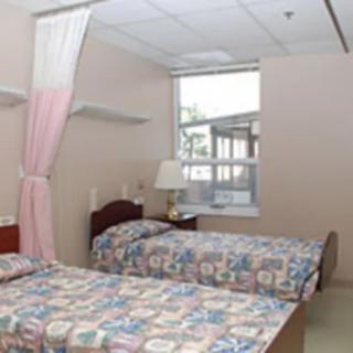 A hospital room with two twin beds and a window letting in natural light.