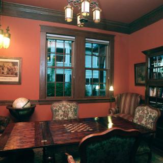 A cozy vintage study room with a chessboard on the table and bookshelves in the background.