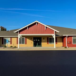 A single-story building with a red and beige facade under a clear blue sky.