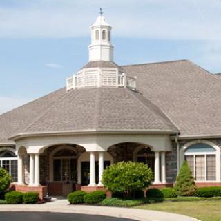 A building with a large roof, featuring a prominent entrance with columns and well-maintained landscaping.