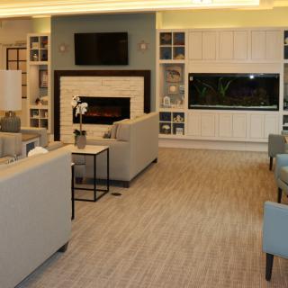 A modern living room with comfortable seating, a fireplace, a television, and a large aquarium.