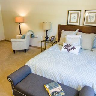 A cozy bedroom with a comfortable bed, armchair, and stylish decor.