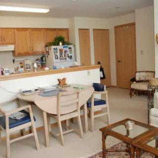 A cozy apartment kitchen with a dining area, featuring light wooden furniture and neutral tones.