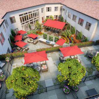 A beautifully landscaped courtyard featuring outdoor seating with red umbrellas.