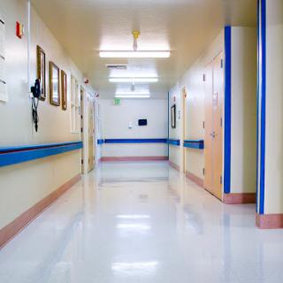 A clean and well-lit hallway in a hospital, featuring blue accents along the walls.