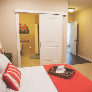 A cozy bedroom with a sliding door leading to the bathroom, featuring comfortable bedding and tasteful decor.