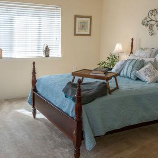 A cozy bedroom with a neatly made bed, featuring a tray and decorative pillows.