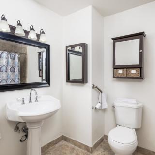 A well-organized bathroom with a pedestal sink and a wall-mounted toilet.