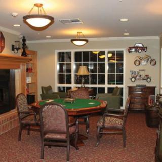 A cozy game room featuring a poker table surrounded by chairs, with decorative elements and warm lighting.
