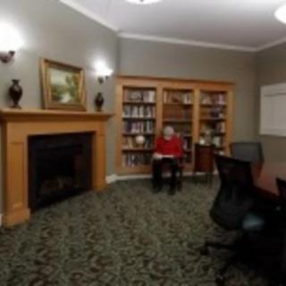 A cozy library room with a fireplace, bookshelves, and seating area.