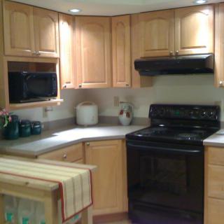 A cozy kitchen with wooden cabinets and black appliances.