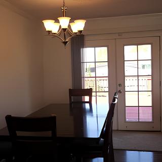 A dining room with a table, chairs, and a chandelier near glass doors leading outside.