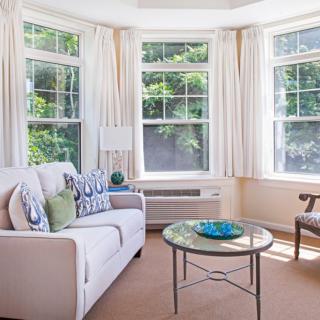 A bright and cozy living room with bay windows and comfortable seating.