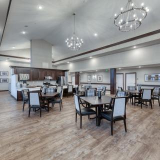 A spacious, elegantly designed dining area featuring modern chandeliers and a comfortable seating arrangement with wood flooring.