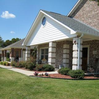 A suburban house with a porch and well-maintained lawn.