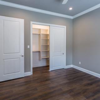 An empty room with hardwood floors and a walk-in closet.
