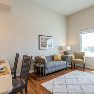 A cozy living room with modern decor featuring a sofa, chairs, and a bright window.