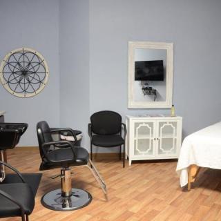 A modern salon interior with styling chairs, a mirror, and a massage table.