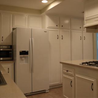 A modern kitchen with white cabinets and appliances.