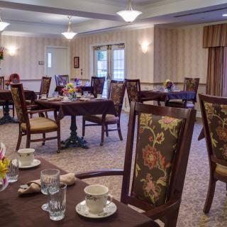 Elegant dining room with neatly arranged tables and chairs, featuring warm lighting and tasteful decor.