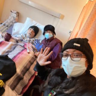 Family members visit a patient in the hospital, all wearing masks.