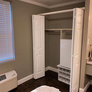 An empty closet with open doors and a shelving unit inside.