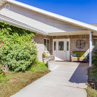 A welcoming entrance to a charming house with lush greenery and a cozy porch.