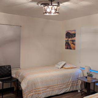 A cozy bedroom featuring two beds, a stylish chandelier, and a modern chair.