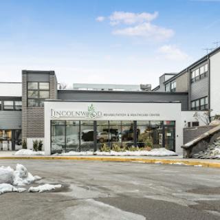 A modern commercial building with a sleek design, partially covered in snow during winter.