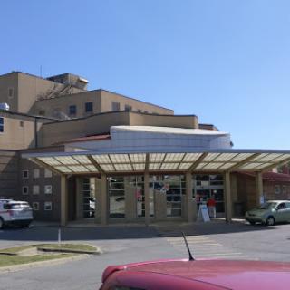 A view of a hospital building with a covered entrance on a clear day.