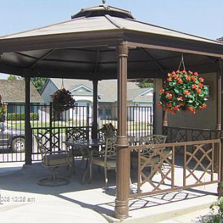 A stylish gazebo with outdoor furniture and hanging plants, providing a shaded area in the backyard.