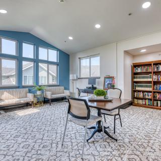 A modern living room with large windows, comfortable seating, and a bookshelf.