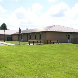 A single-story brick building surrounded by a green lawn under a partly cloudy sky.