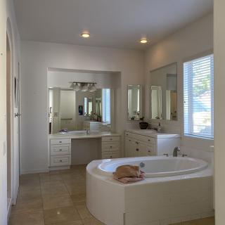 A modern bathroom with a bathtub and a cat resting on it.