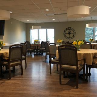 A spacious and well-lit dining room featuring tables set with flowers, creating a welcoming atmosphere.