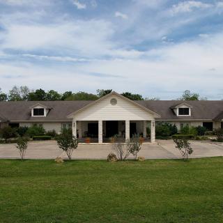 A large residential house with a wide driveway and landscaped front yard.