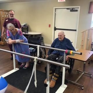 Elderly individuals participating in a rehabilitation session with assistance from staff.