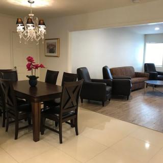 A spacious dining and living area featuring a wooden dining table, chairs, a chandelier, and comfortable seating arrangements.