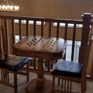 A cozy indoor setup with a wooden game table and chairs overlooking a balcony.