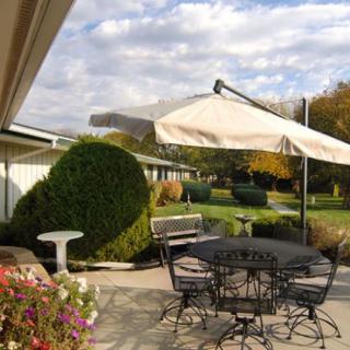 A peaceful patio setting with a table, chairs, and umbrella overlooking a well-maintained garden.