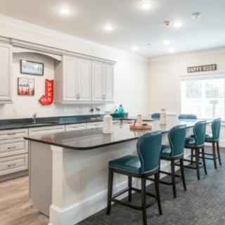 A modern kitchen with a spacious island and stylish bar stools under bright lighting.