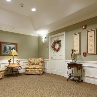 A cozy living room with a floral sofa, decorative lamp, and framed artwork on the wall.