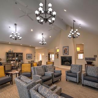 A spacious and elegant living room with cozy seating, chandeliers, and a fireplace.